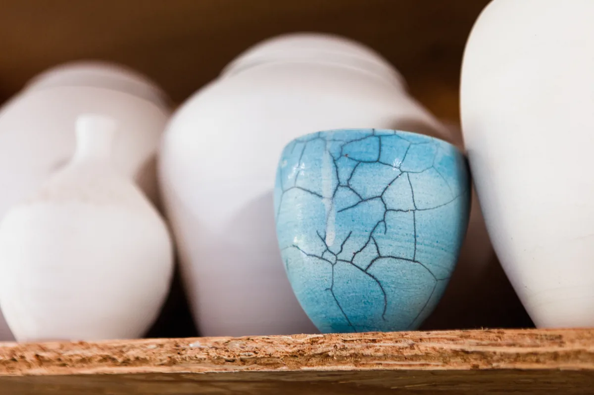 Un bol en céramique craquelée bleue entre des pièces blanches