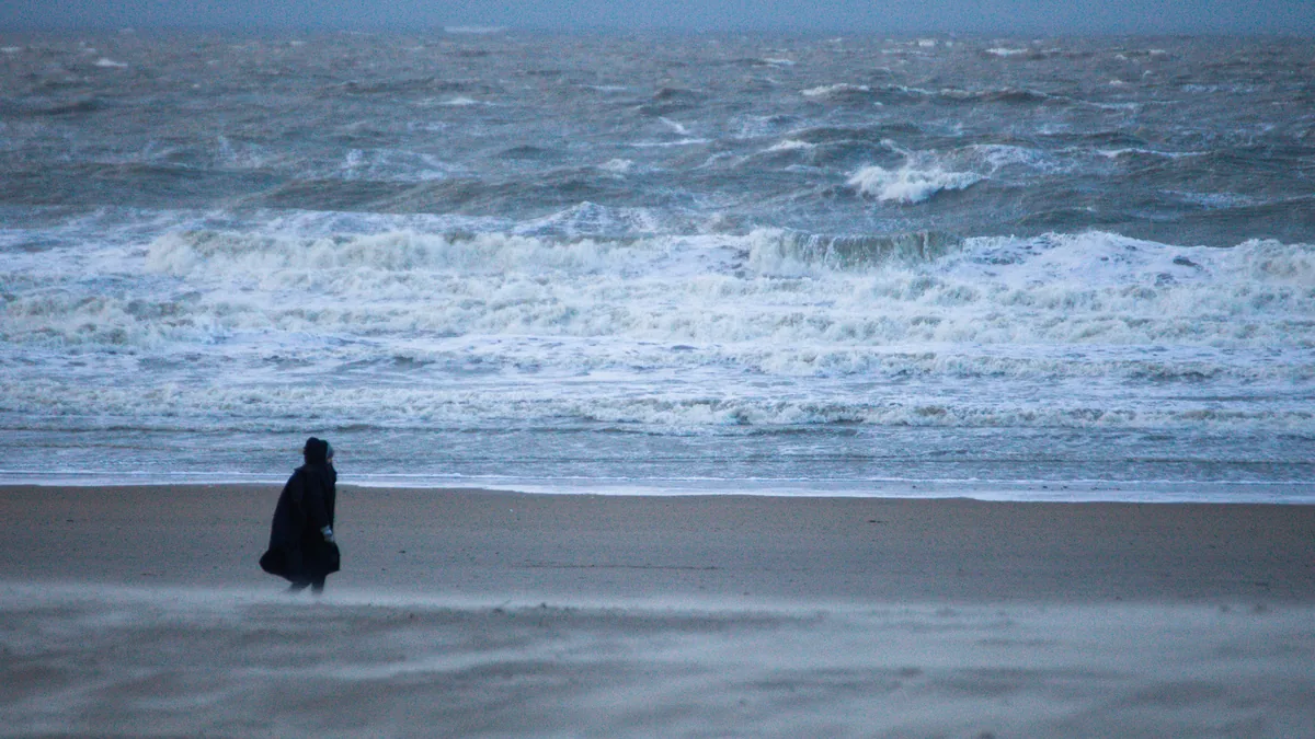 Une silhouette sur une plage face à la mer agitée